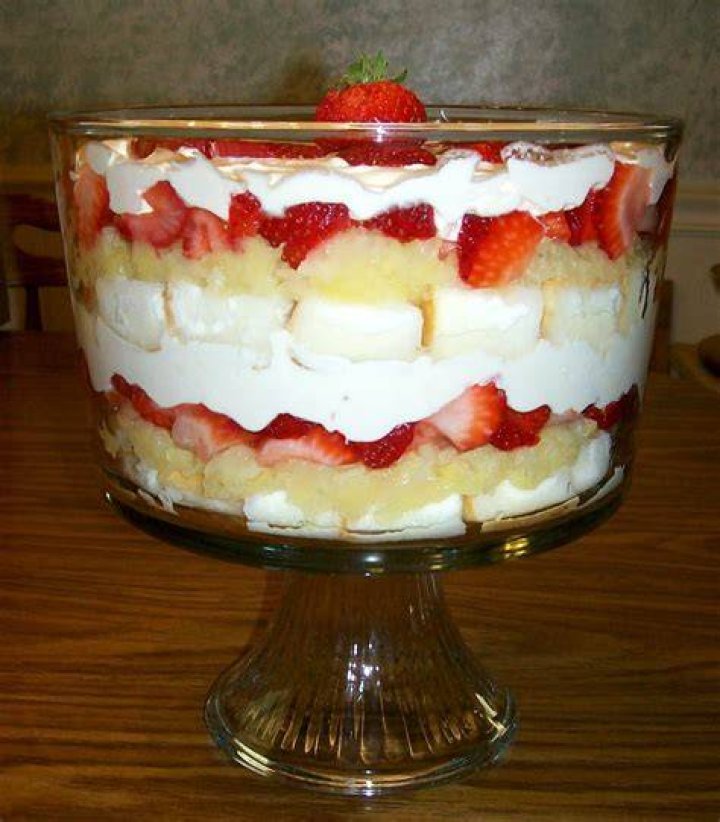 Glass trifle dish with layers of brownies, whipped cream, and fudge.
