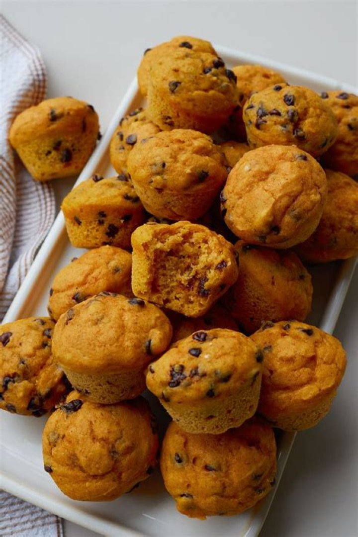 Pumpkin muffins next to a gold knife with butter on it.
