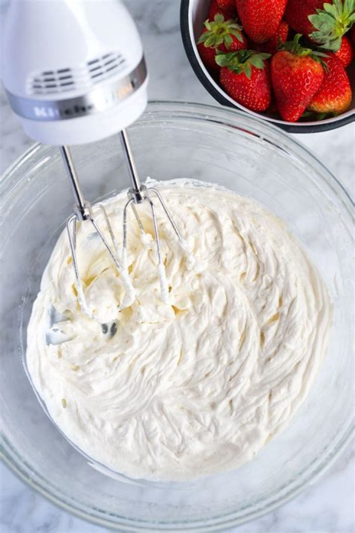 Spreading whipped cream over layers of pudding, cookies and banana. 